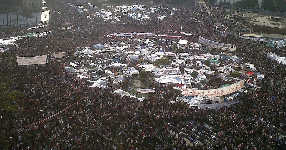 An aerial photograph of a large crowd of people gathered in Tahrir Square.