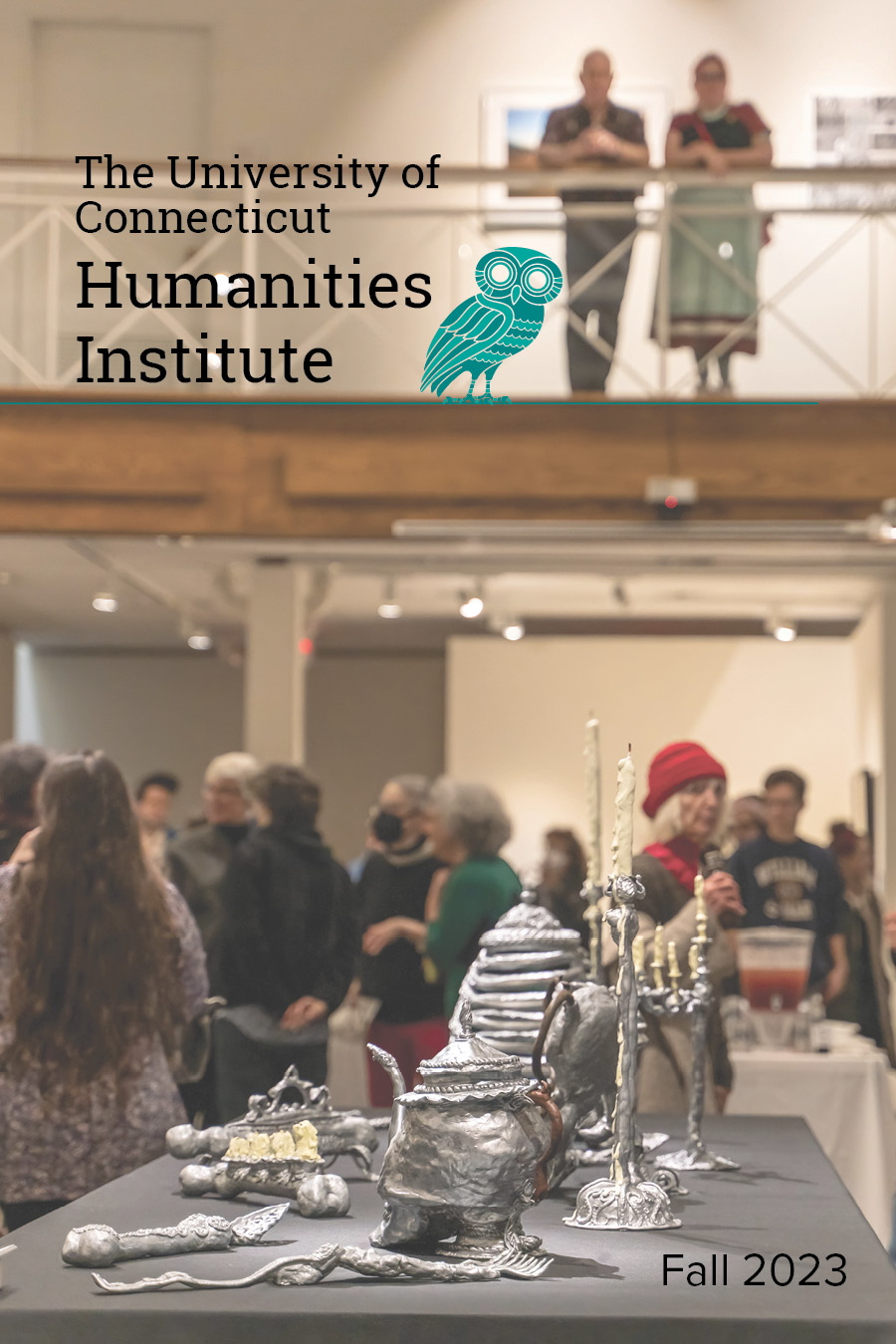 Cover of our Fall 2023 Year in Review booklet, featuring an image of the opening of the Seeing Truth exhibition at the William Benton Museum of Art. In the foreground of the image Valerie Hegarty's art piece Silver Skeleton is visible. The piece showcases a table service seemingly made of a mixture of silver and human bones. In the background a crowd of people look at art.